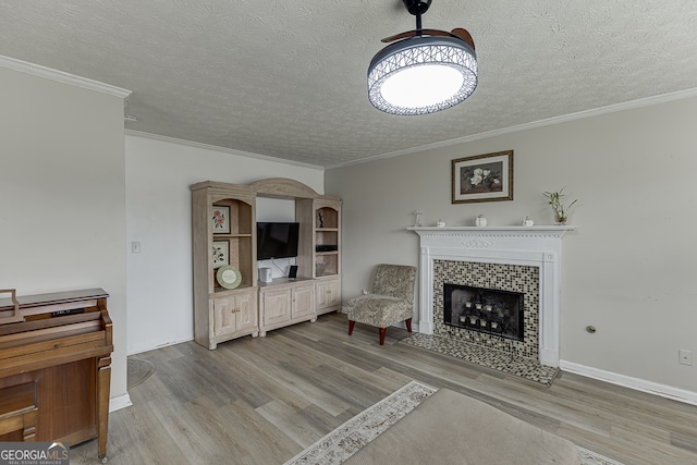 living room featuring a fireplace, a textured ceiling, light wood-type flooring, and ornamental molding