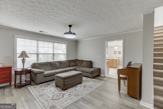 living room featuring ceiling fan, a textured ceiling, light hardwood / wood-style flooring, and crown molding