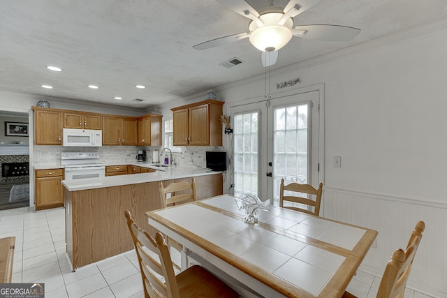 kitchen with sink, kitchen peninsula, light tile patterned floors, white appliances, and french doors