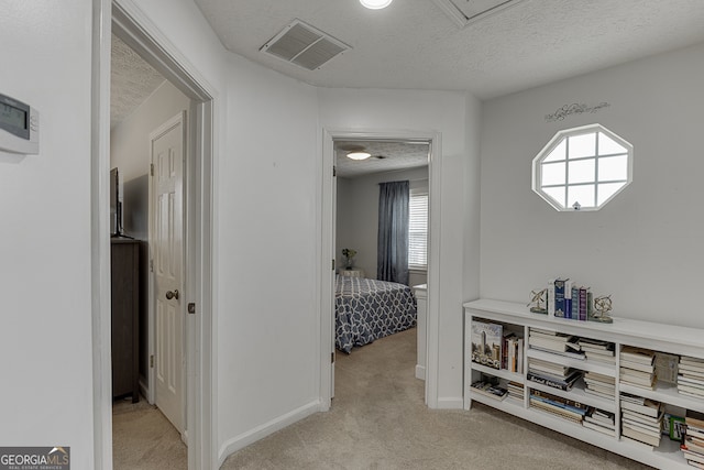 hallway featuring a textured ceiling and light carpet