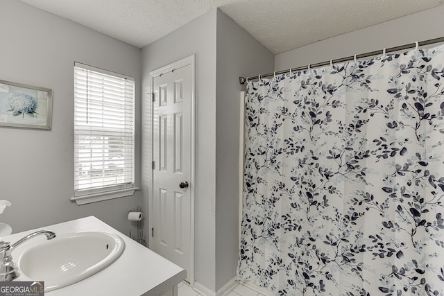 bathroom with walk in shower, vanity, and a textured ceiling