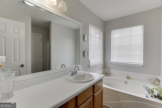 bathroom with a bath, a textured ceiling, and vanity