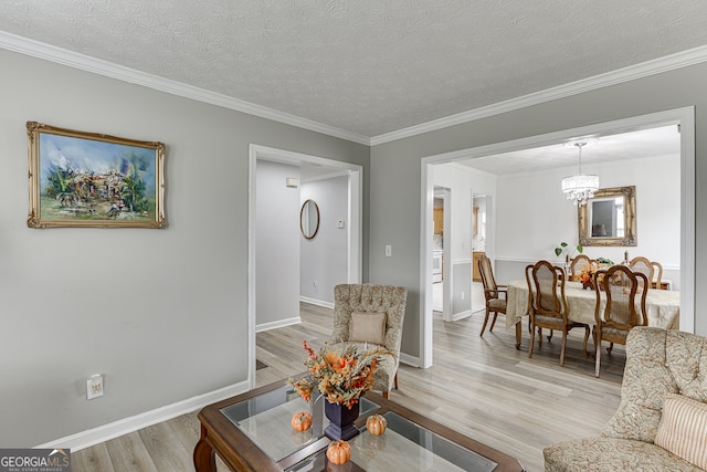 living room with light hardwood / wood-style floors, a notable chandelier, a textured ceiling, and crown molding