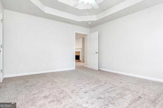 carpeted empty room with a tray ceiling and ceiling fan