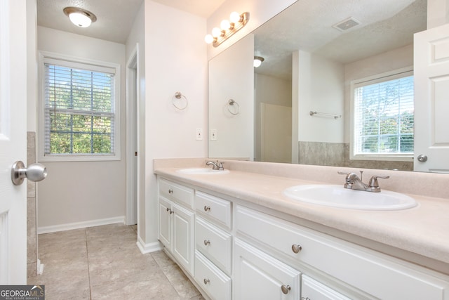 bathroom featuring a textured ceiling, vanity, and a healthy amount of sunlight