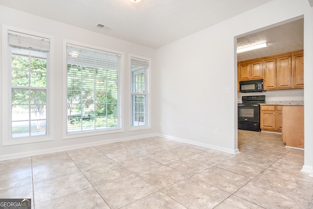 interior space featuring a wealth of natural light, black appliances, and light tile patterned flooring