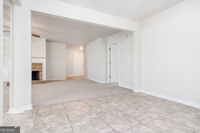 unfurnished living room with a brick fireplace, a textured ceiling, and light carpet