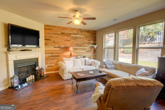 living room featuring ceiling fan, dark hardwood / wood-style flooring, and wooden walls