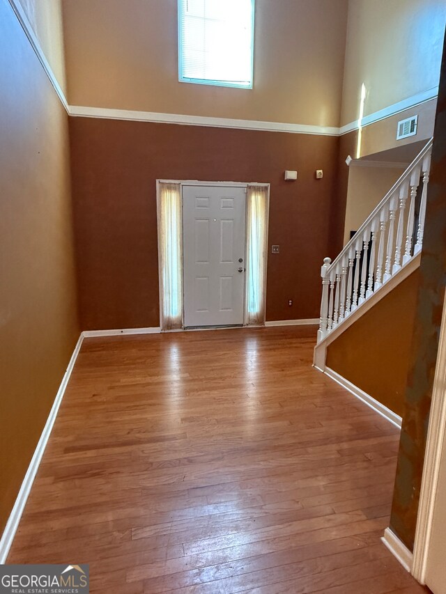 entryway with wood-type flooring and a towering ceiling