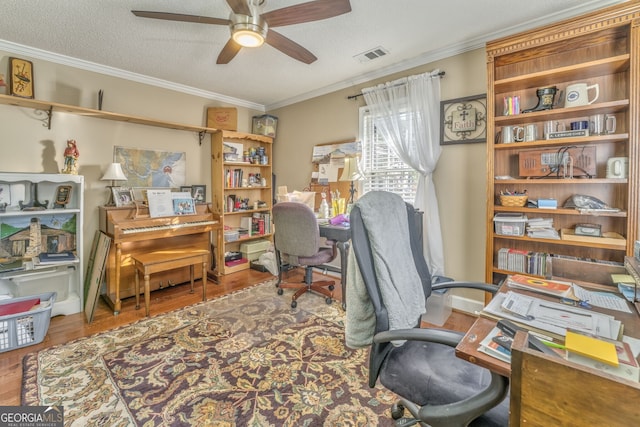 home office with a ceiling fan, visible vents, crown molding, and wood finished floors