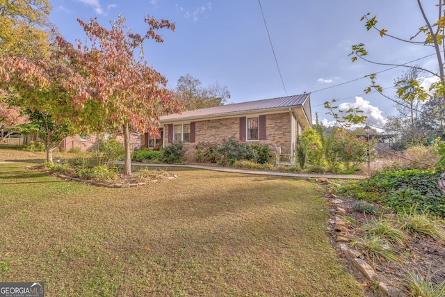 view of front of home with brick siding, metal roof, and a front lawn