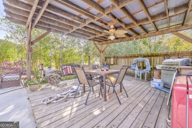 wooden deck featuring a ceiling fan, outdoor dining area, fence, and grilling area