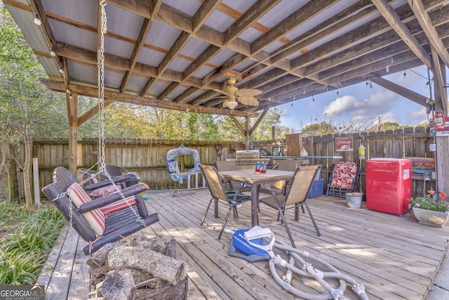 wooden terrace featuring outdoor dining space, a fenced backyard, and ceiling fan