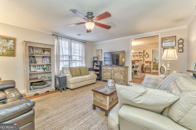 living area featuring a textured ceiling, ornamental molding, visible vents, and a ceiling fan