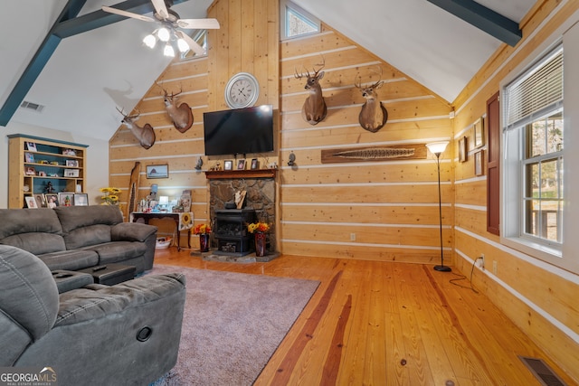 living room with hardwood / wood-style floors, beamed ceiling, a healthy amount of sunlight, and a wood stove