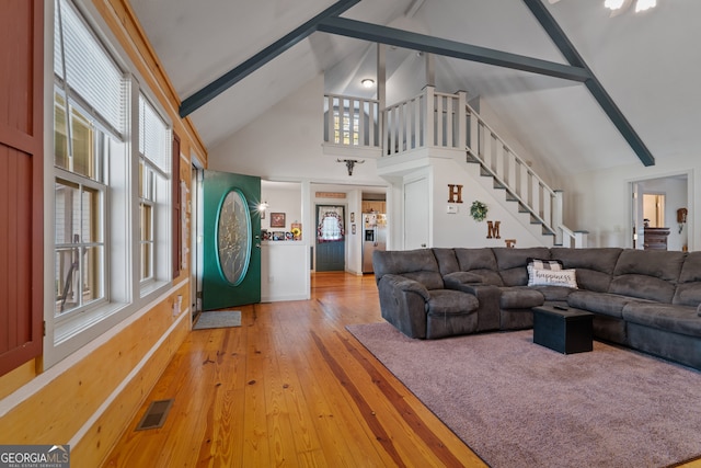 living room with hardwood / wood-style flooring, beamed ceiling, and high vaulted ceiling