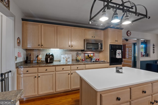 kitchen featuring appliances with stainless steel finishes, light brown cabinetry, a center island, light wood-type flooring, and decorative backsplash