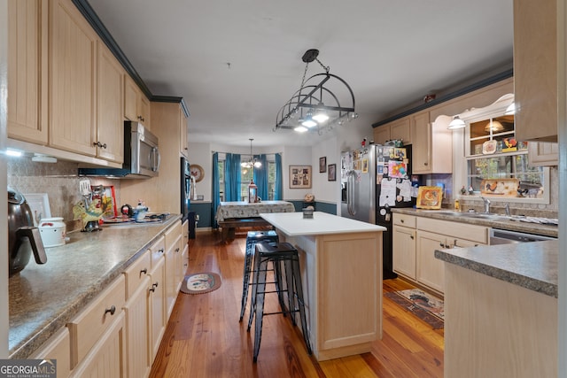 kitchen featuring hardwood / wood-style floors, a chandelier, a kitchen island, a breakfast bar, and pendant lighting