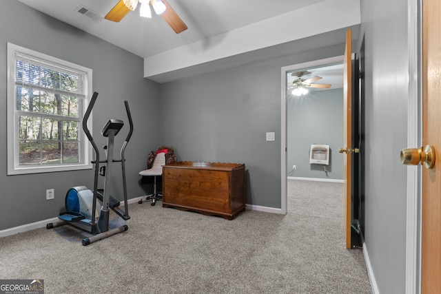 workout room featuring light colored carpet, ceiling fan, and heating unit