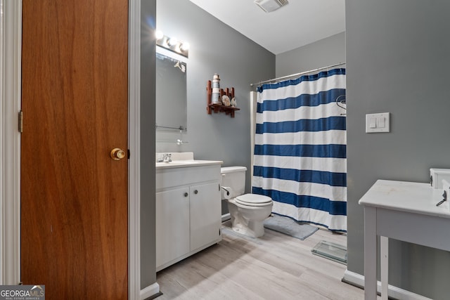 bathroom featuring a shower with shower curtain, hardwood / wood-style flooring, vanity, and toilet