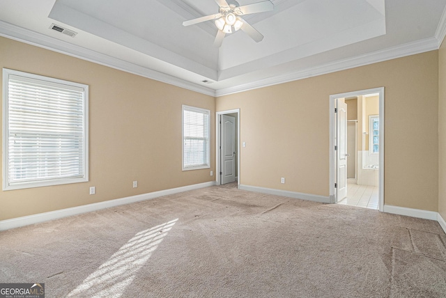 carpeted empty room featuring ceiling fan, ornamental molding, a wealth of natural light, and a tray ceiling