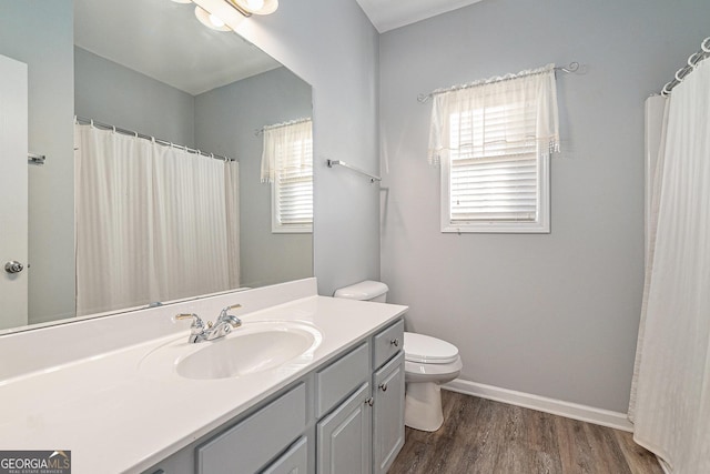 bathroom featuring a wealth of natural light, hardwood / wood-style floors, vanity, and toilet