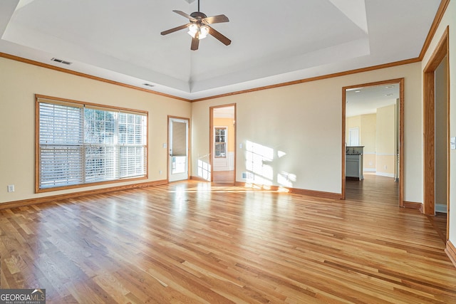 unfurnished room featuring a tray ceiling, ceiling fan, crown molding, and light hardwood / wood-style floors