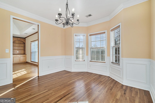 unfurnished dining area featuring wood-type flooring, an inviting chandelier, and crown molding