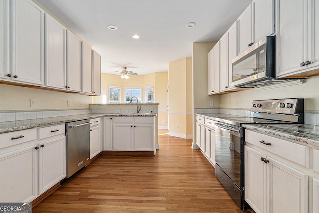 kitchen featuring white cabinets, stainless steel appliances, light hardwood / wood-style flooring, and ceiling fan