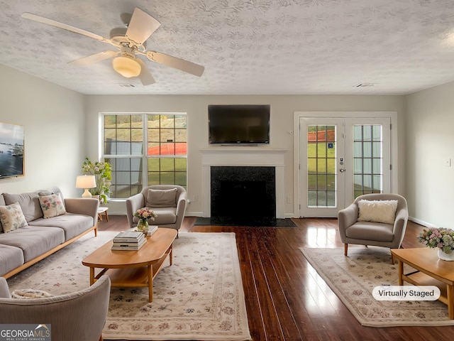 living room with a wealth of natural light, dark wood-type flooring, and a textured ceiling