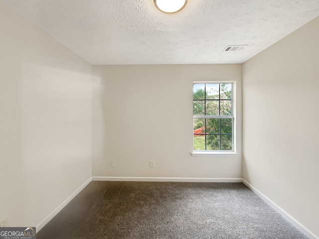 carpeted empty room featuring a textured ceiling