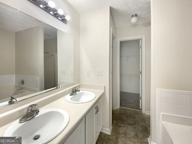 bathroom with vanity, a bath, and a textured ceiling