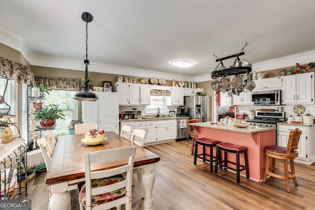 kitchen with a kitchen island, white cabinetry, appliances with stainless steel finishes, and light wood-type flooring