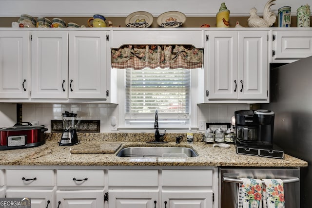 kitchen with decorative backsplash, light stone countertops, sink, and white cabinets