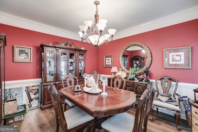 dining area with light wood-type flooring, crown molding, and an inviting chandelier