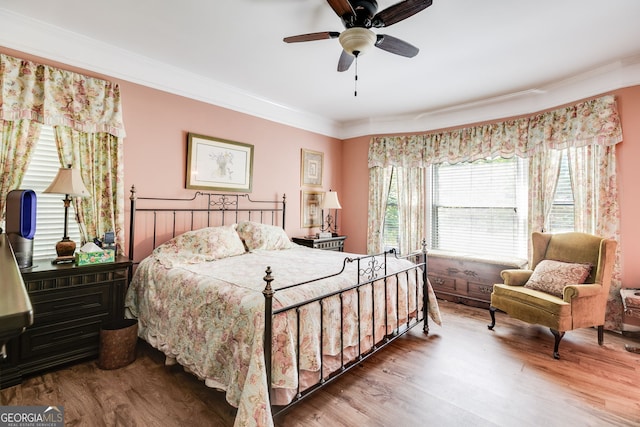 bedroom featuring ornamental molding, wood-type flooring, ceiling fan, and wooden walls