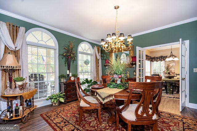 dining area with ornamental molding, hardwood / wood-style floors, a wealth of natural light, and a chandelier