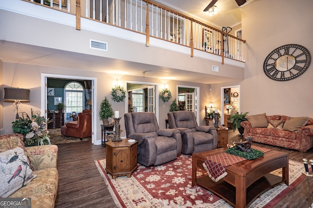 living room with a towering ceiling, ceiling fan, and dark wood-type flooring