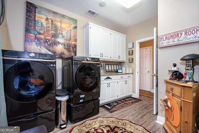 laundry area with cabinets, independent washer and dryer, and light wood-type flooring