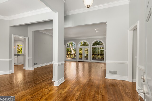 entryway featuring ornamental molding, decorative columns, and dark wood-type flooring