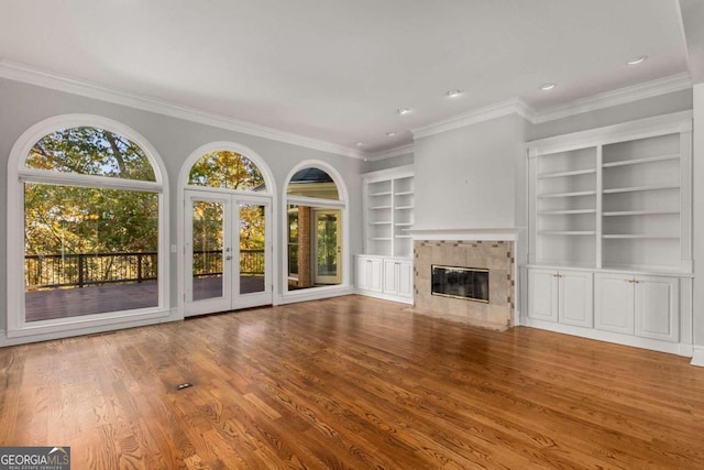 unfurnished living room with a high end fireplace, ornamental molding, and hardwood / wood-style flooring