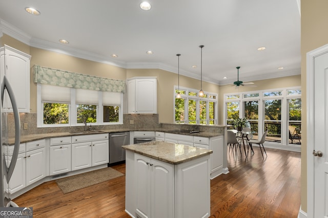 kitchen featuring white cabinets, decorative light fixtures, kitchen peninsula, and appliances with stainless steel finishes