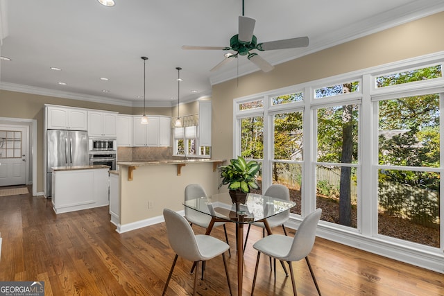 dining area with ceiling fan, dark hardwood / wood-style flooring, and ornamental molding