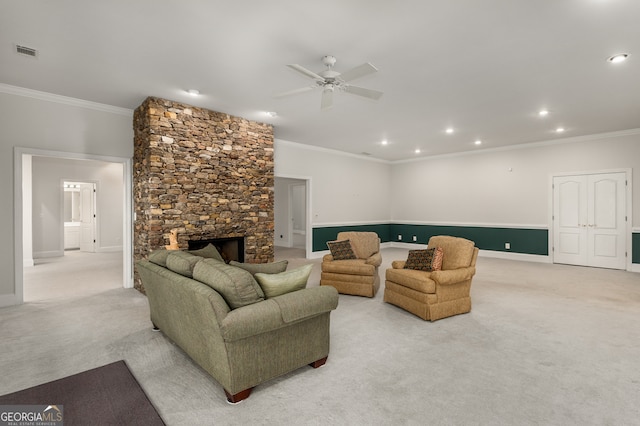 carpeted living room featuring a fireplace, ceiling fan, and crown molding