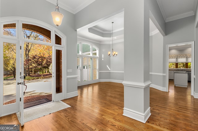 foyer with ornamental molding, hardwood / wood-style flooring, a healthy amount of sunlight, and a notable chandelier