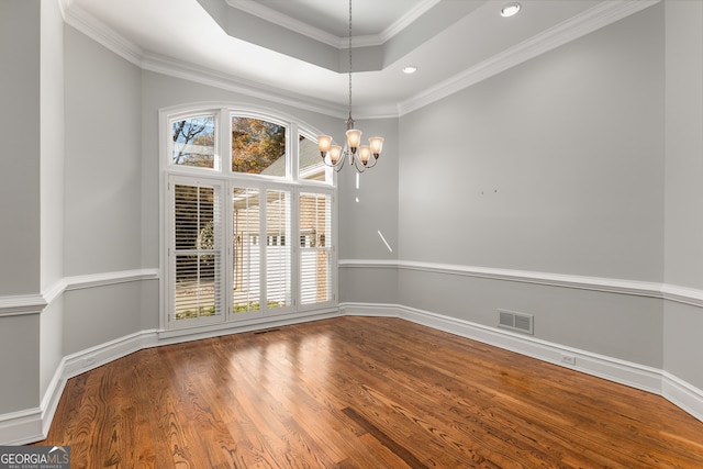 unfurnished dining area featuring hardwood / wood-style flooring, crown molding, and an inviting chandelier