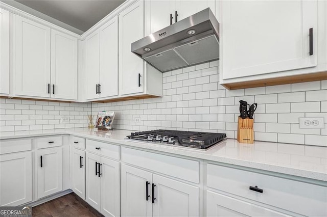 kitchen with tasteful backsplash, light stone countertops, dark hardwood / wood-style floors, stainless steel gas stovetop, and white cabinets