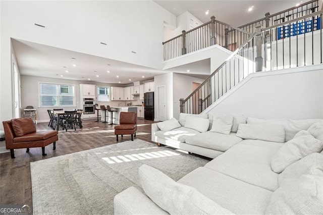 living room with dark hardwood / wood-style flooring and a towering ceiling