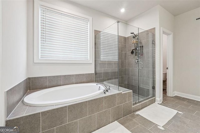 bathroom featuring toilet, shower with separate bathtub, and tile patterned flooring