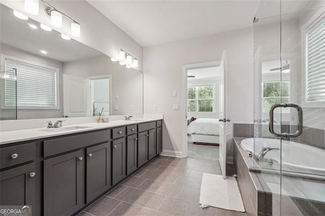 bathroom featuring vanity, a relaxing tiled tub, tile patterned floors, and a healthy amount of sunlight